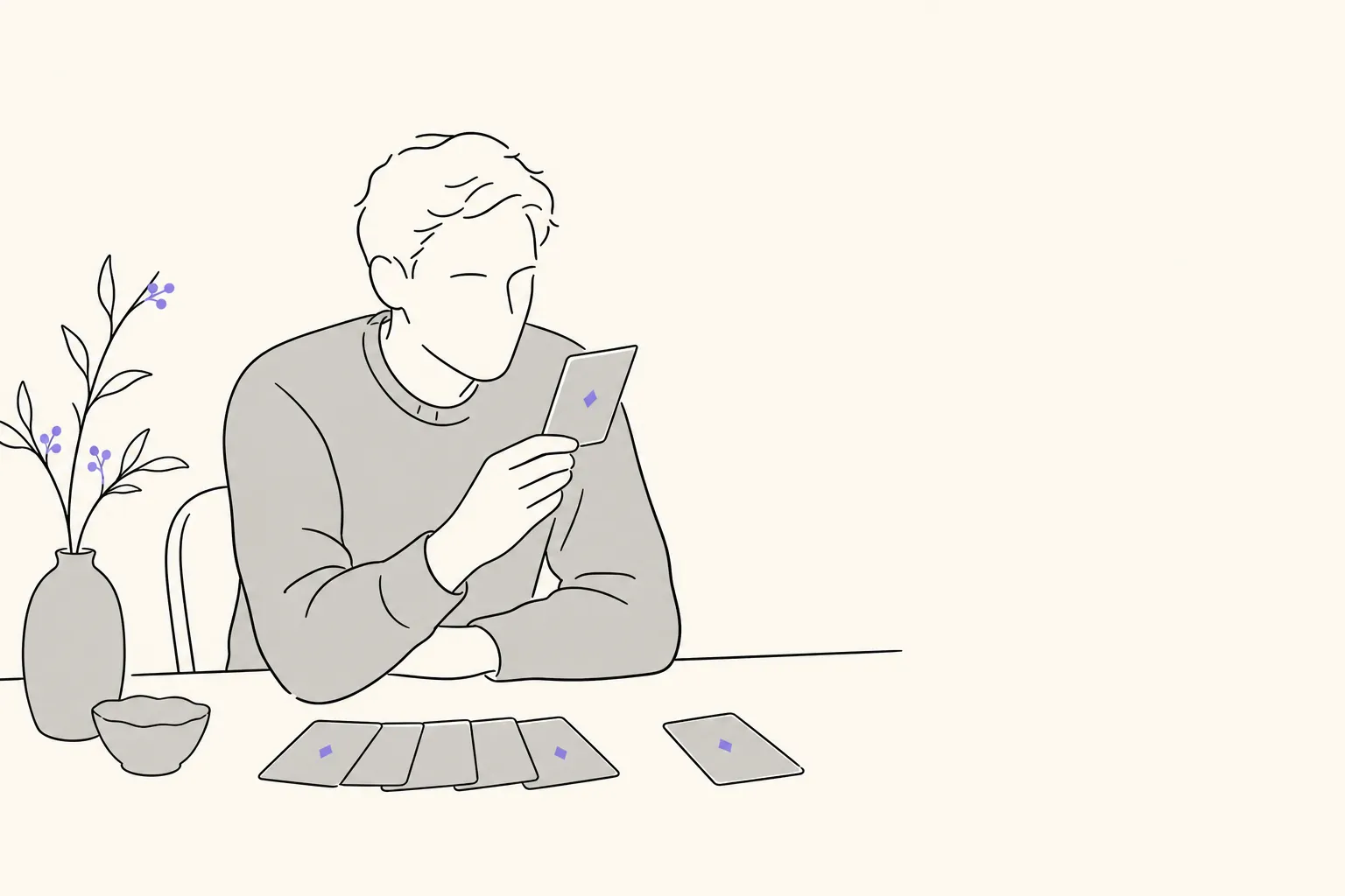 A person at a desk studying a single card held up in their hand, with a few more spread out below.